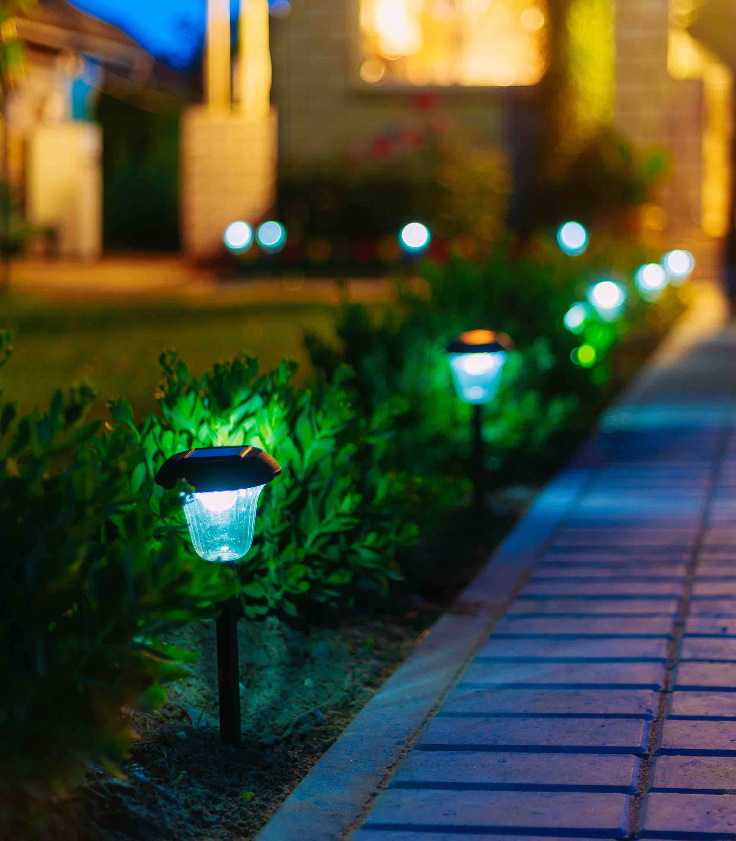 Solar powered lights illuminating a path up to a house - Custom Electrical has many tips to make your home glow!